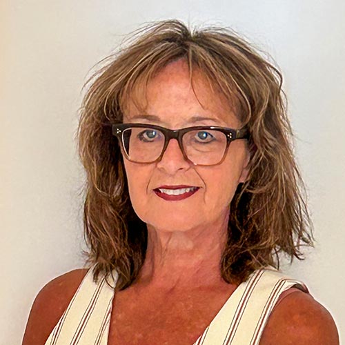 Terri James Author headshot - Older Caucasian woman with Brown shoulder length hair and glasses.