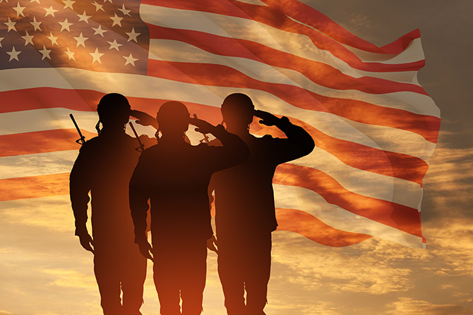 Silhouette of soldiers soluting in front of American flag