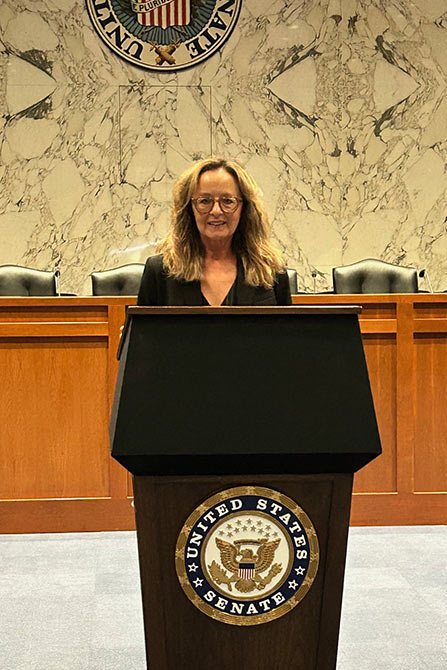Celebrating-125 Years -- Terri James standing at the US Senate podium in the senate chambers.